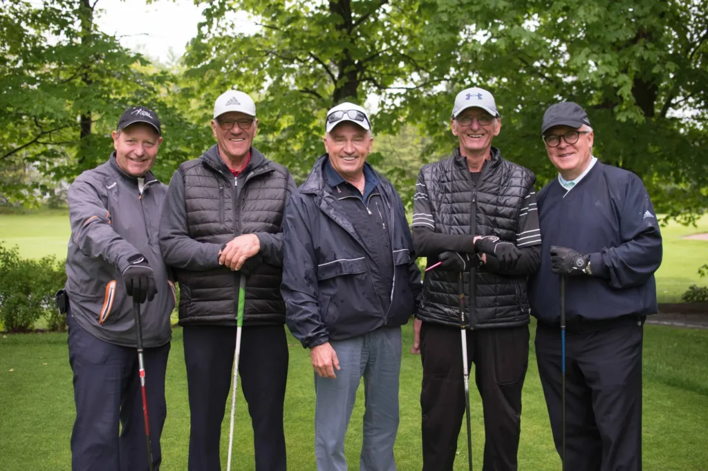 Cinq golfeurs souriants sur un parcours verdoyant