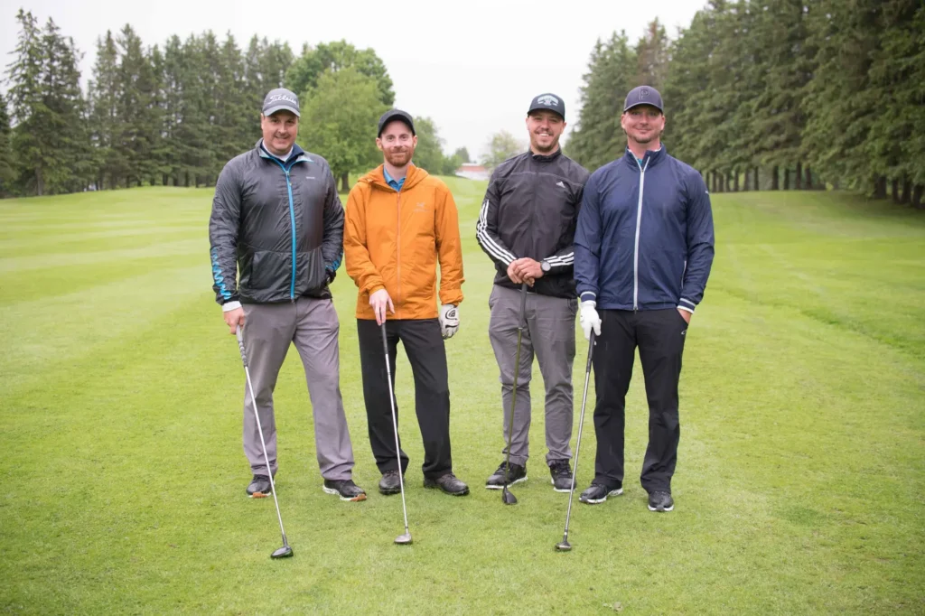 Quatre golfeurs posant sur un parcours verdoyant