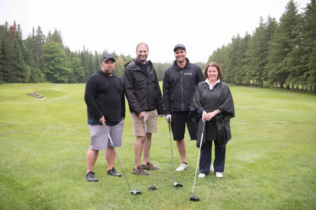 Quatre golfeurs posant sur un parcours verdoyant