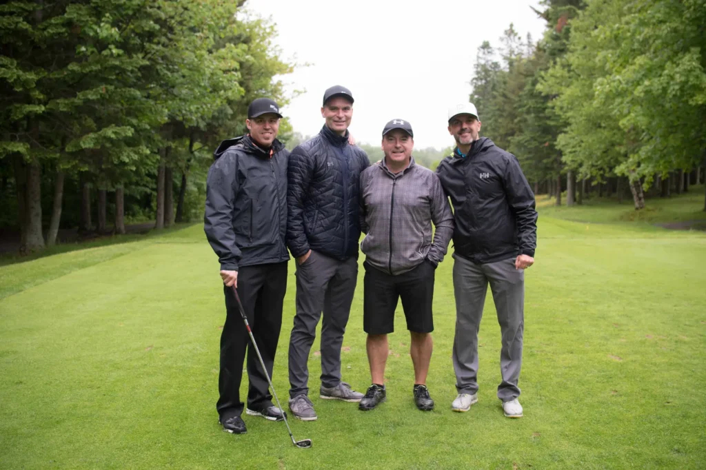 Quatre golfeurs posent sur un parcours verdoyant