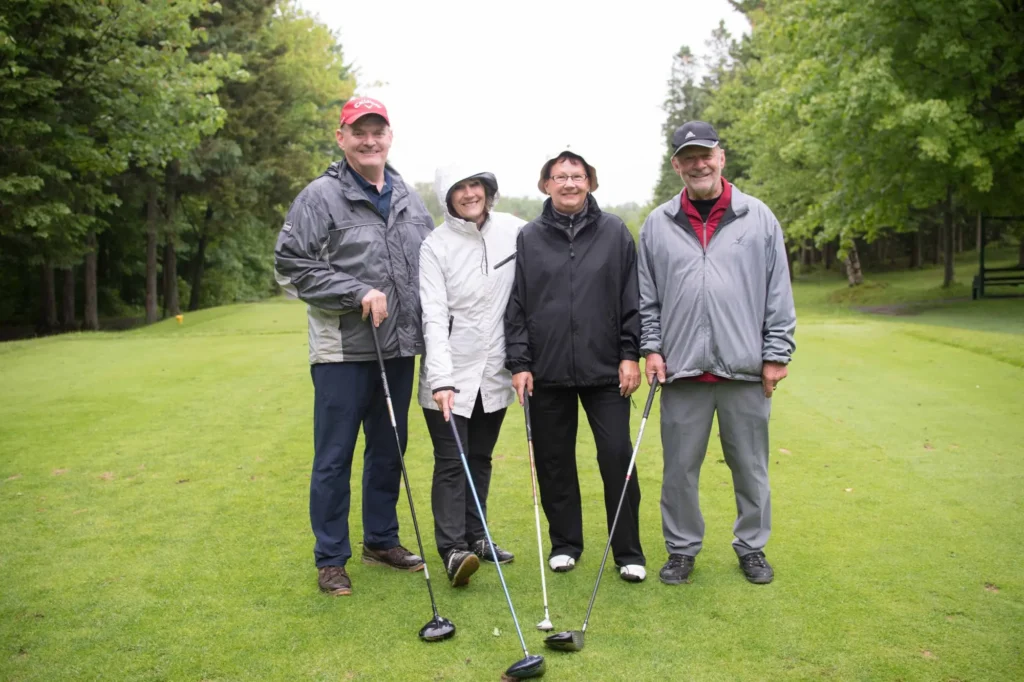 Quatre seniors souriants sur un parcours de golf