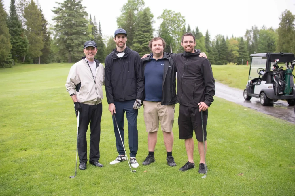 Quatre hommes posant sur un parcours de golf