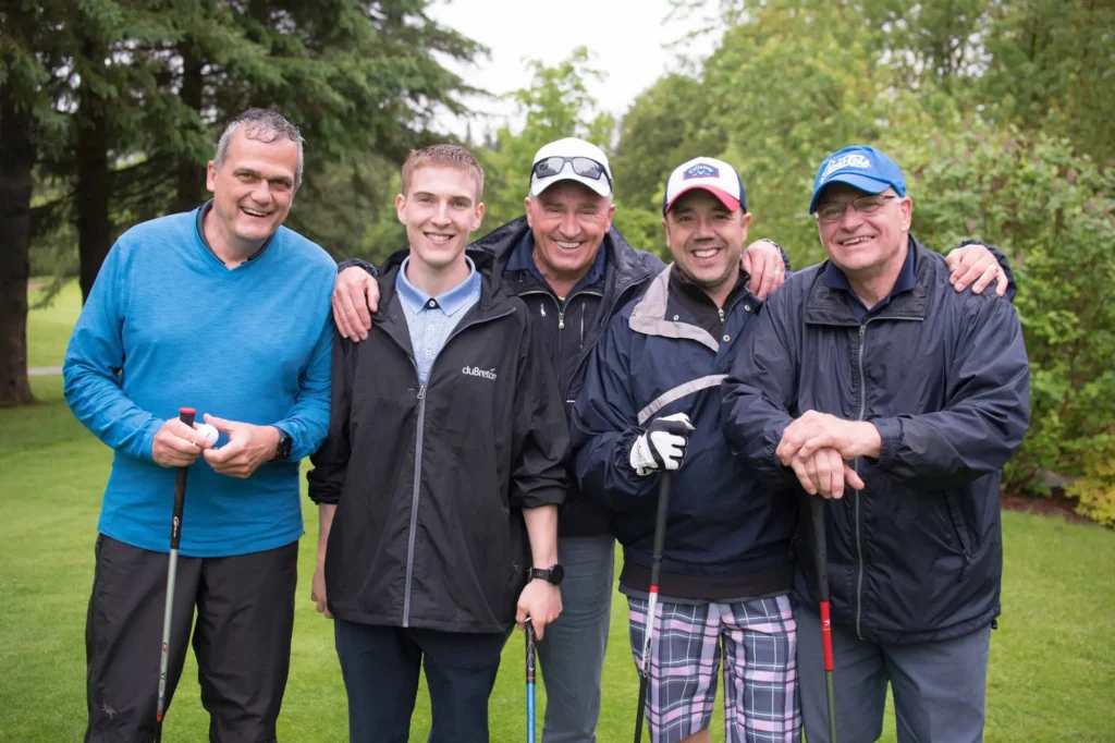 Cinq hommes souriants sur un parcours de golf