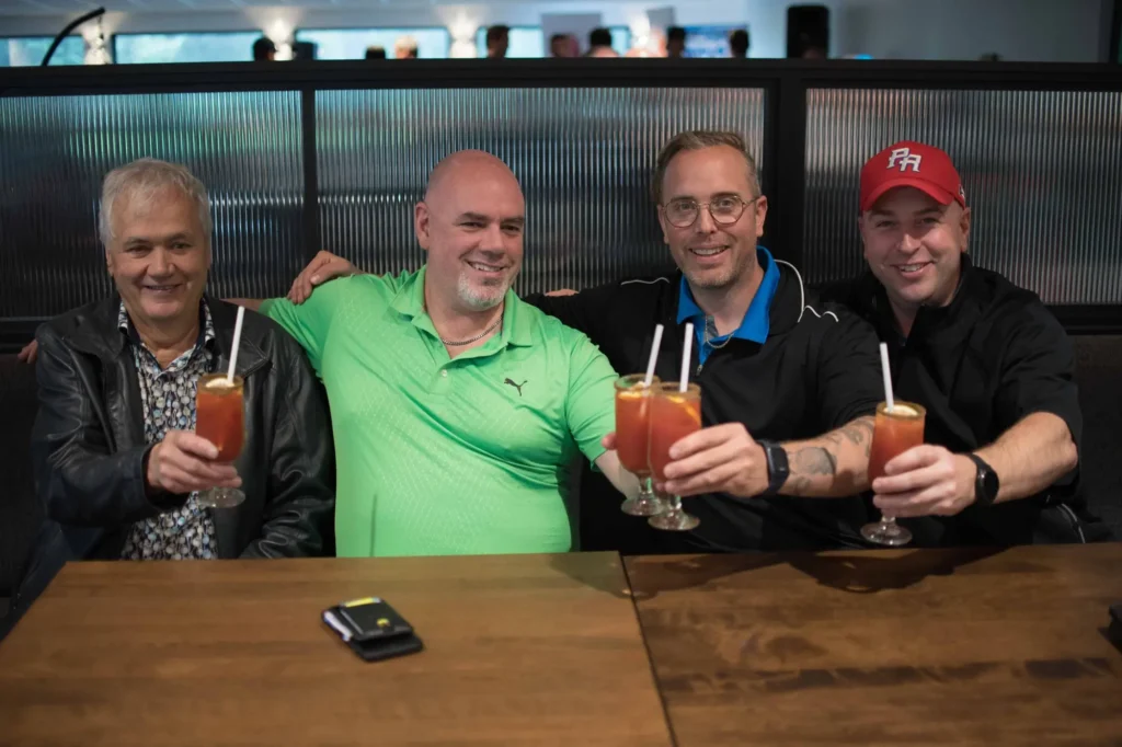 Quatre hommes trinquent avec cocktails au bar
