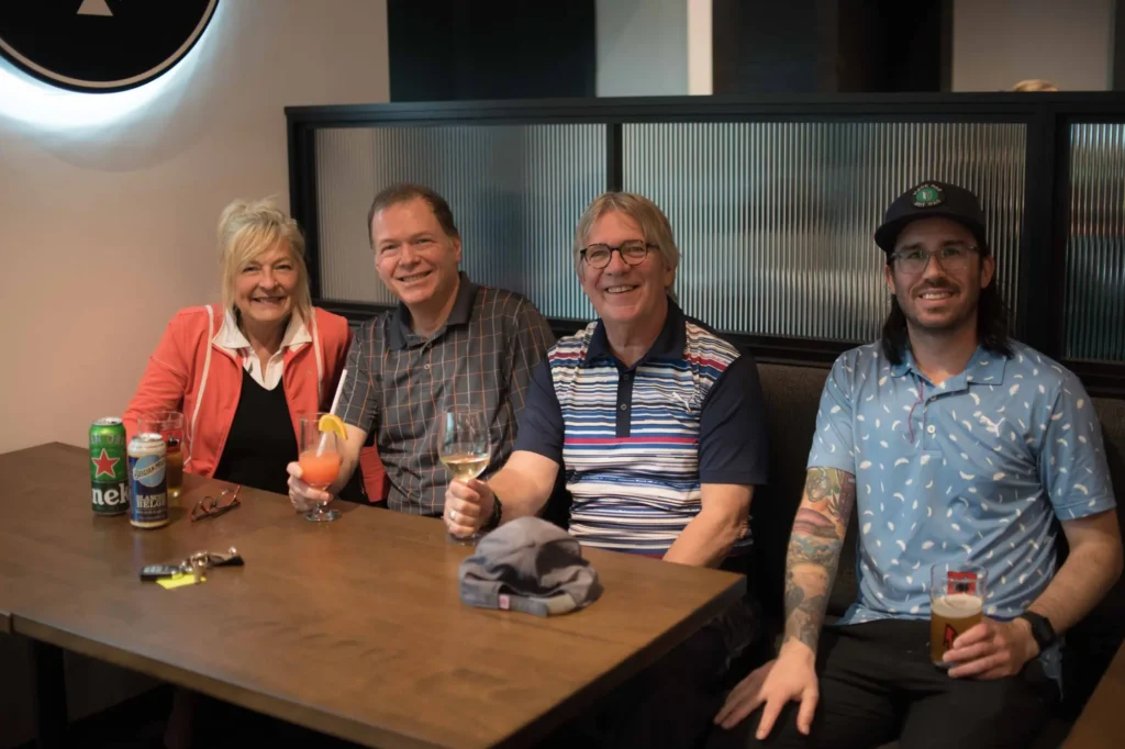 Quatre amis souriant autour de verres au bar