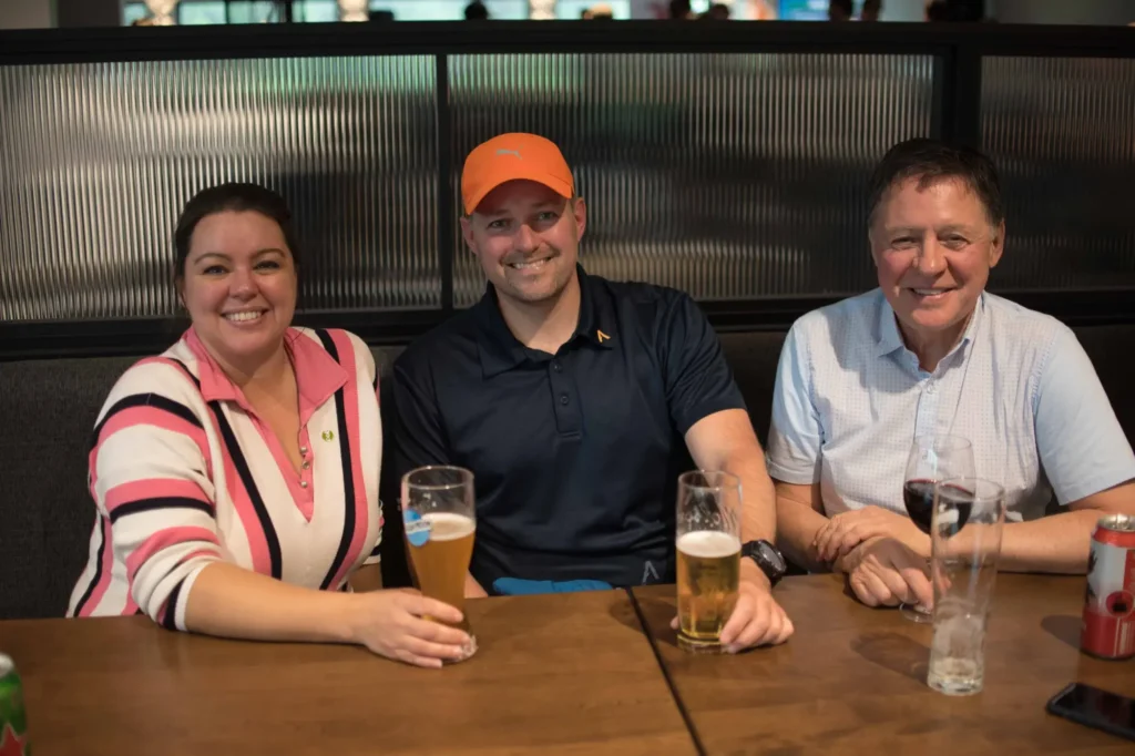 Trois amis souriant autour d’un verre au bar