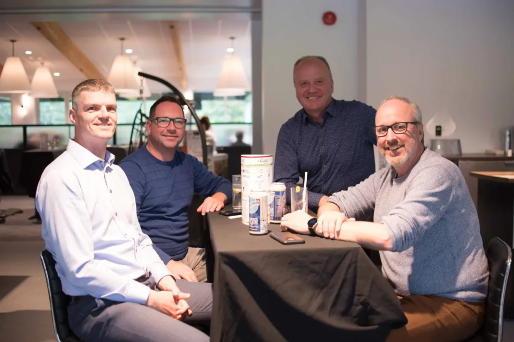 Quatre hommes assis à une table intérieure