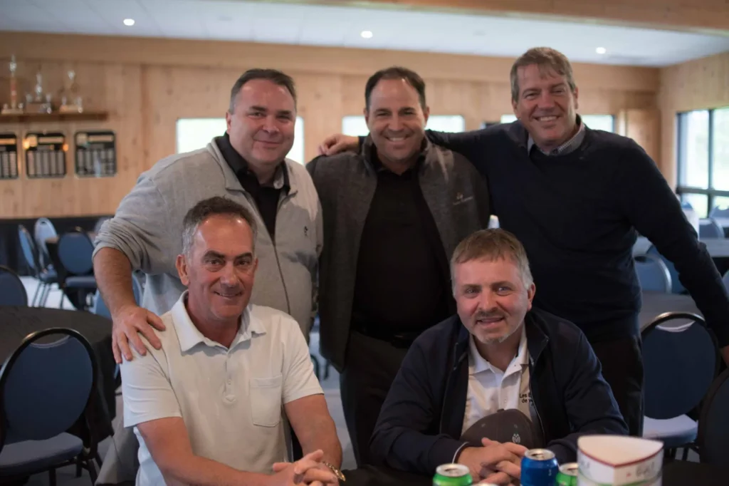 Cinq hommes souriants dans une salle conviviale