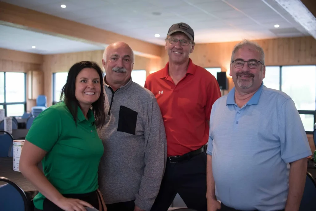 Quatre adultes souriants posant dans une salle lumineuse