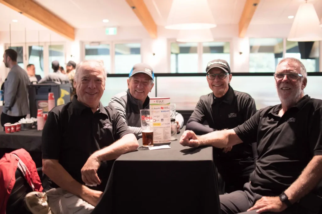Quatre hommes souriants autour d’une table intérieure