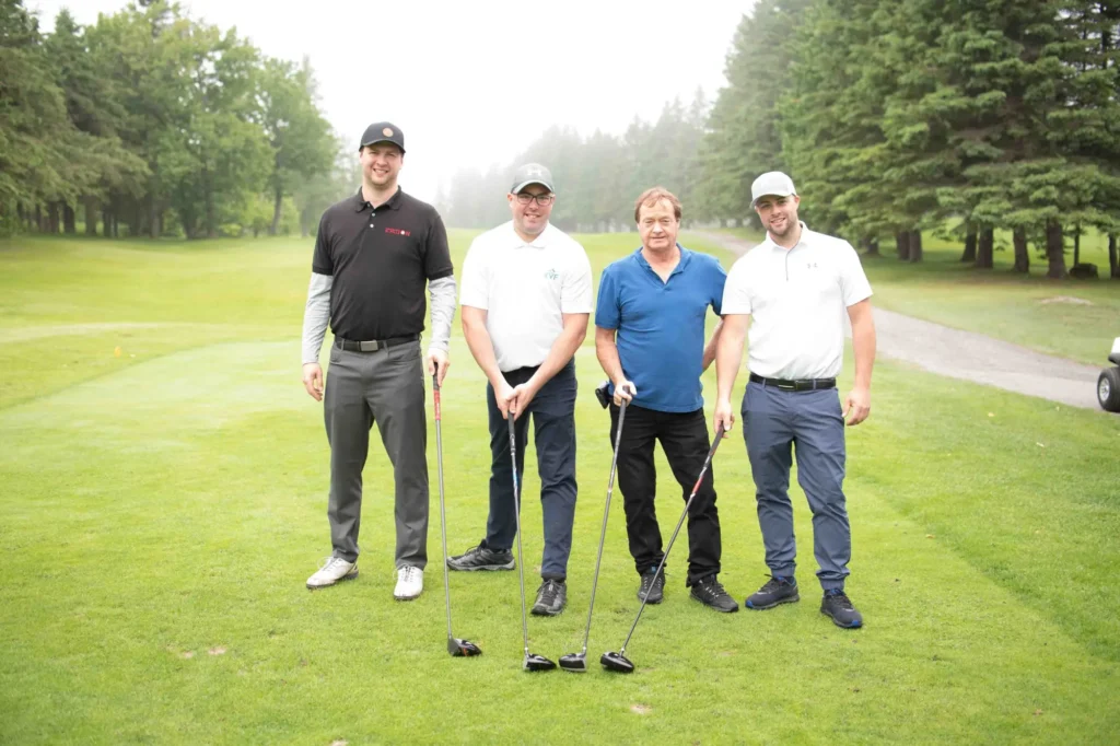 Quatre hommes posant sur un parcours de golf