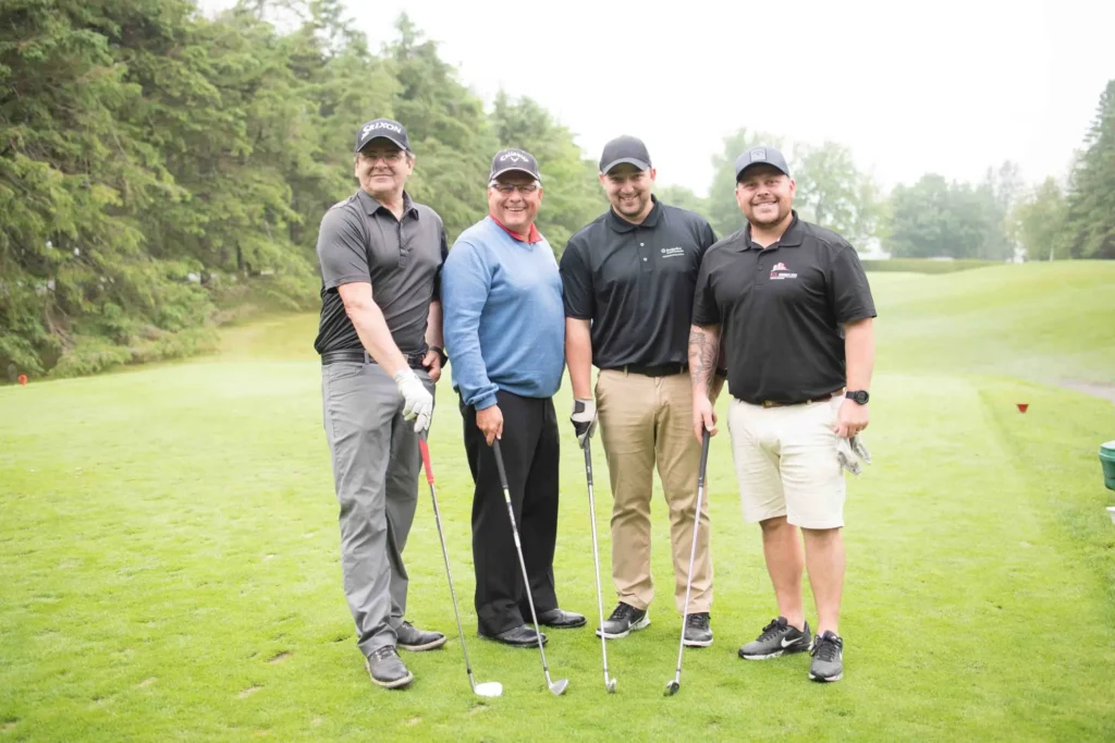 Quatre hommes posant sur un parcours de golf