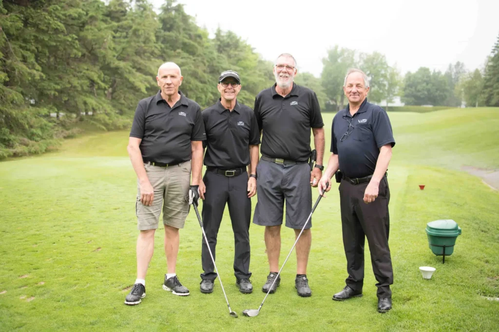 Quatre hommes posant sur un parcours de golf