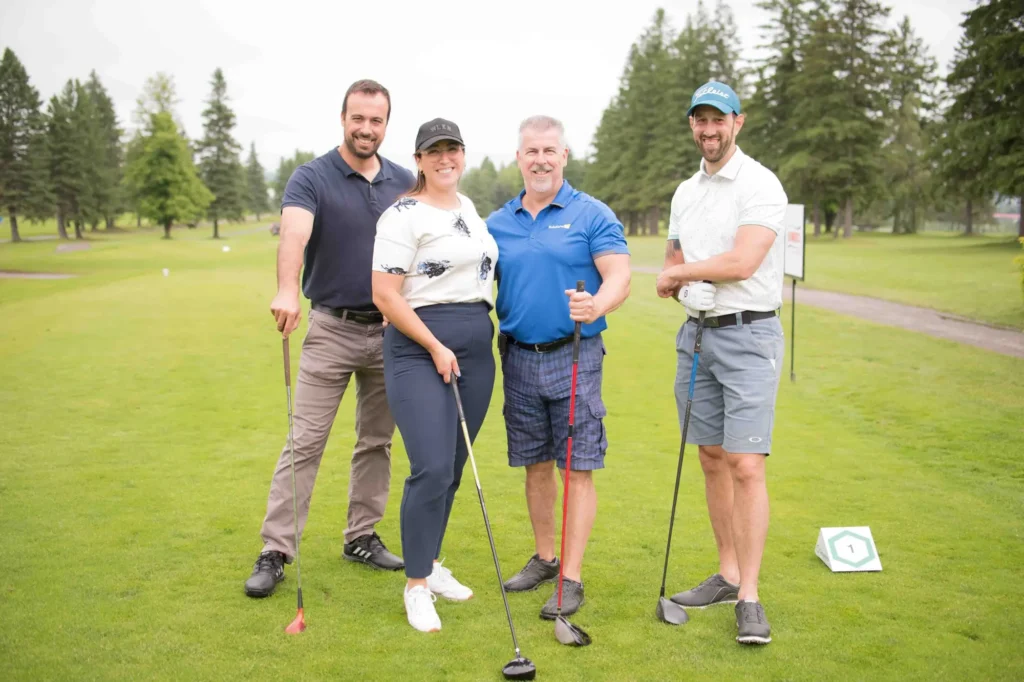 Quatre golfeurs posant sur un parcours verdoyant
