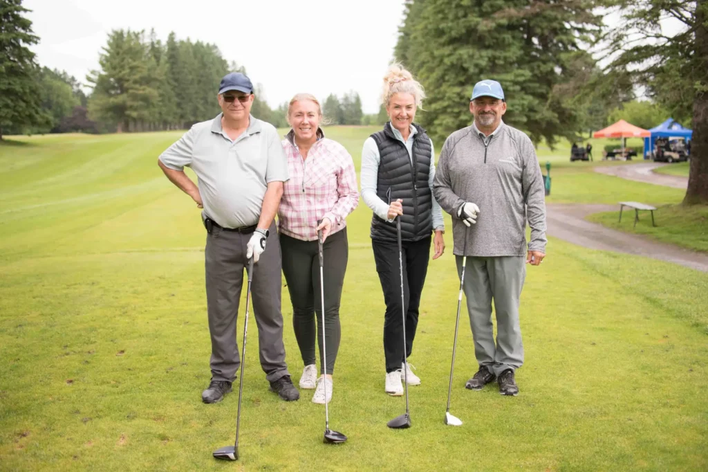 Quatre golfeurs souriants sur un parcours verdoyant