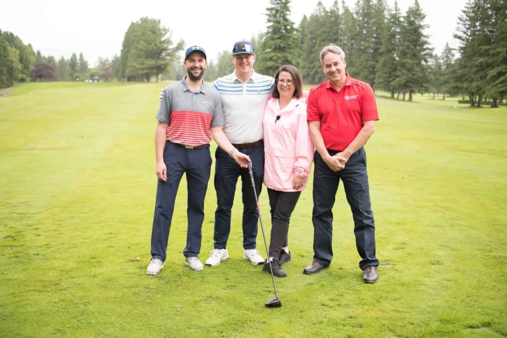 Quatre adultes souriants sur un parcours de golf