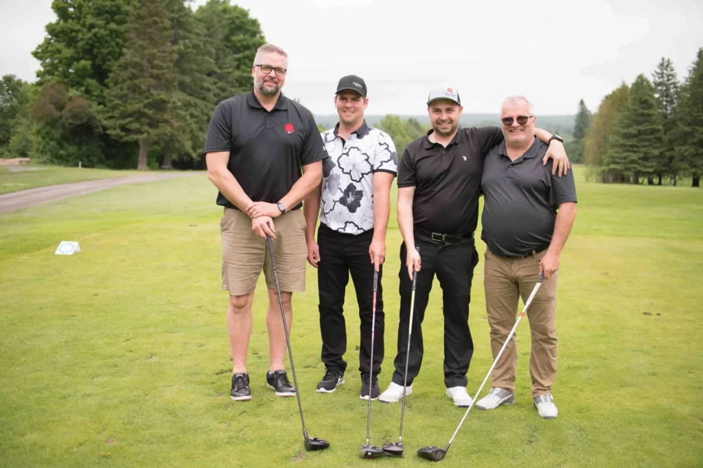 Quatre hommes posant sur un terrain de golf