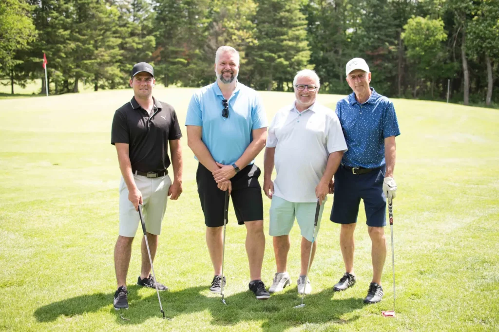 Quatre hommes posant sur un terrain de golf