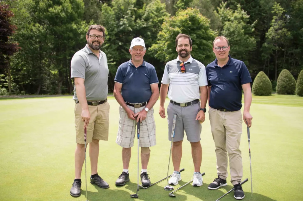 Quatre hommes posant sur un green de golf