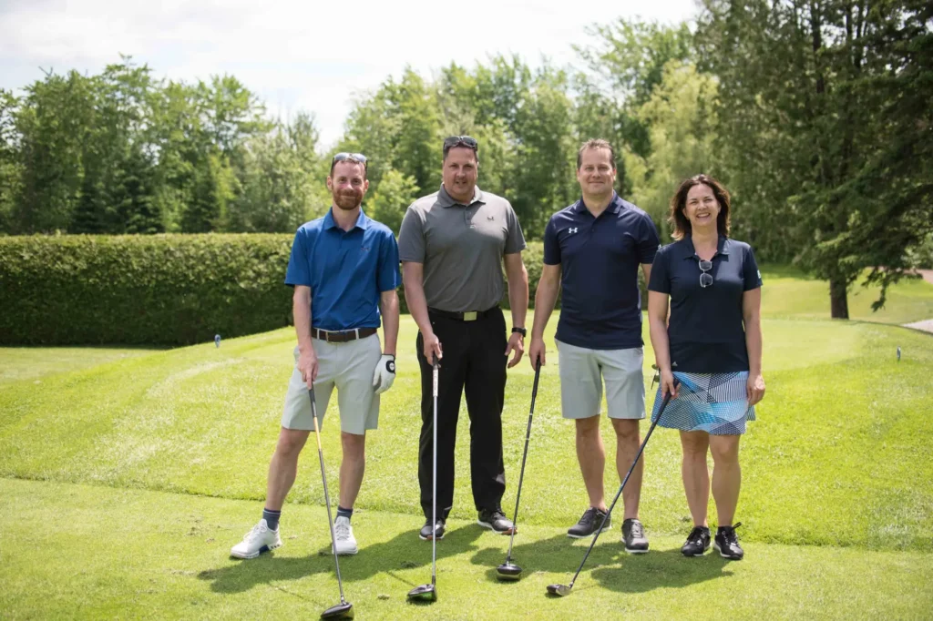 Quatre golfeurs posant sur un parcours verdoyant