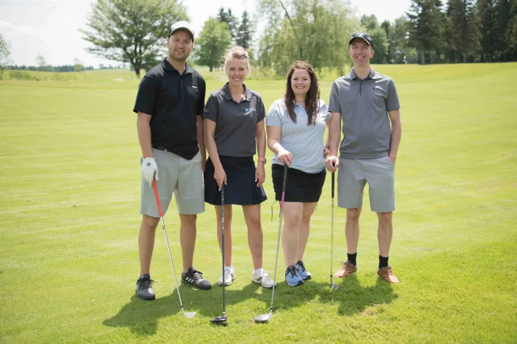 Quatre golfeurs posant sur un parcours verdoyant