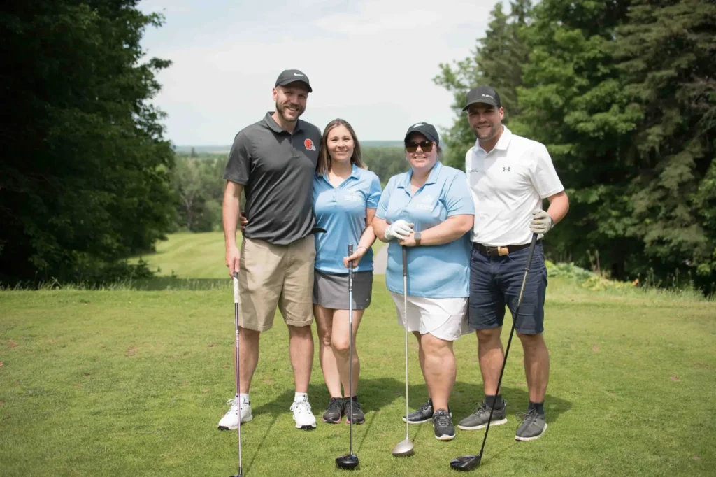 Quatre golfeurs souriants sur un parcours verdoyant