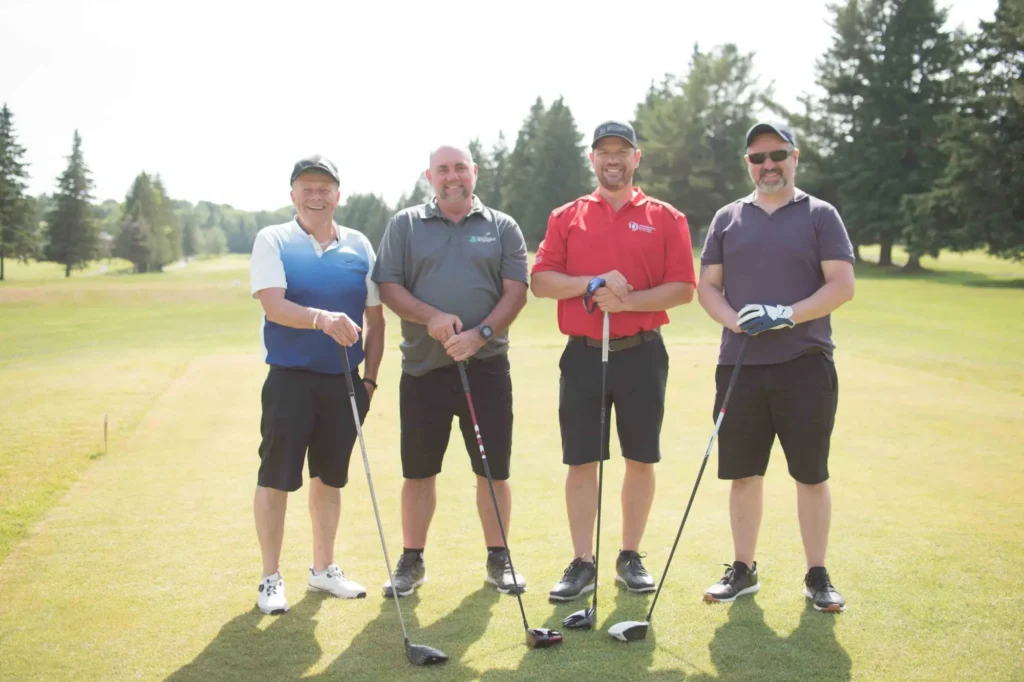 Quatre golfeurs posant sur un parcours ensoleillé