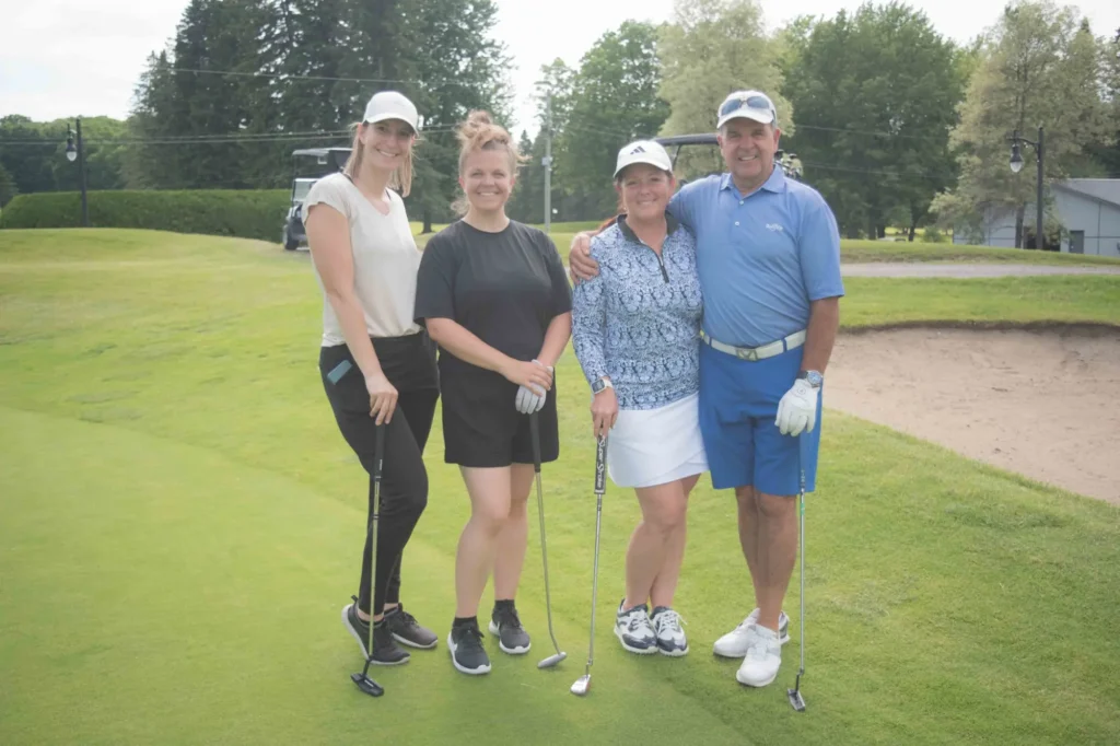 Quatre golfeurs souriants sur un green
