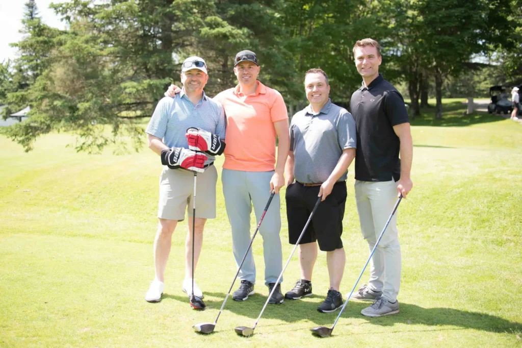 Quatre hommes posent sur un parcours de golf
