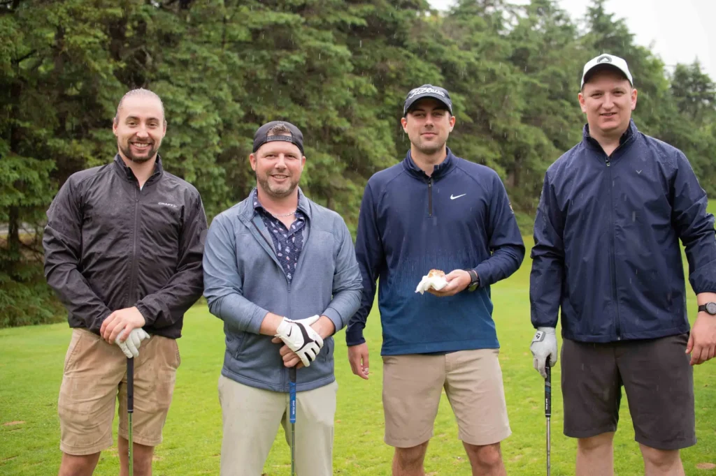 Quatre hommes posent sur un parcours de golf