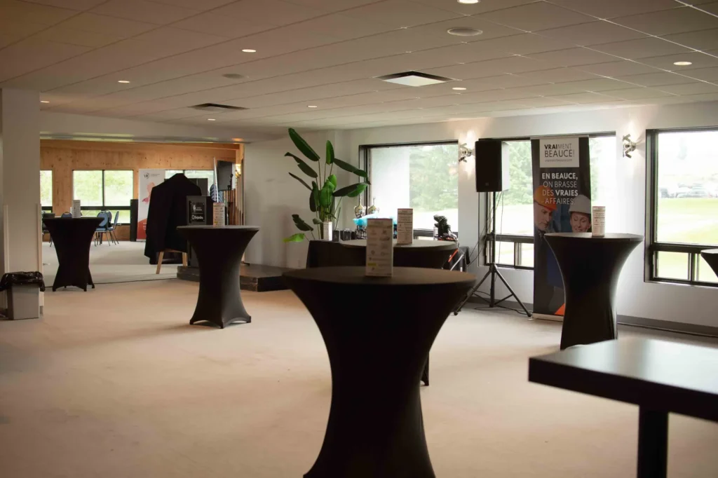 Salle d’événement avec tables hautes et podium