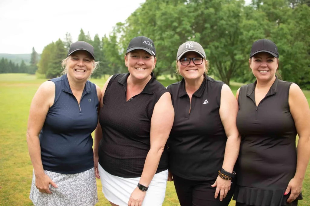 Quatre golfeuses souriantes sur un parcours verdoyant