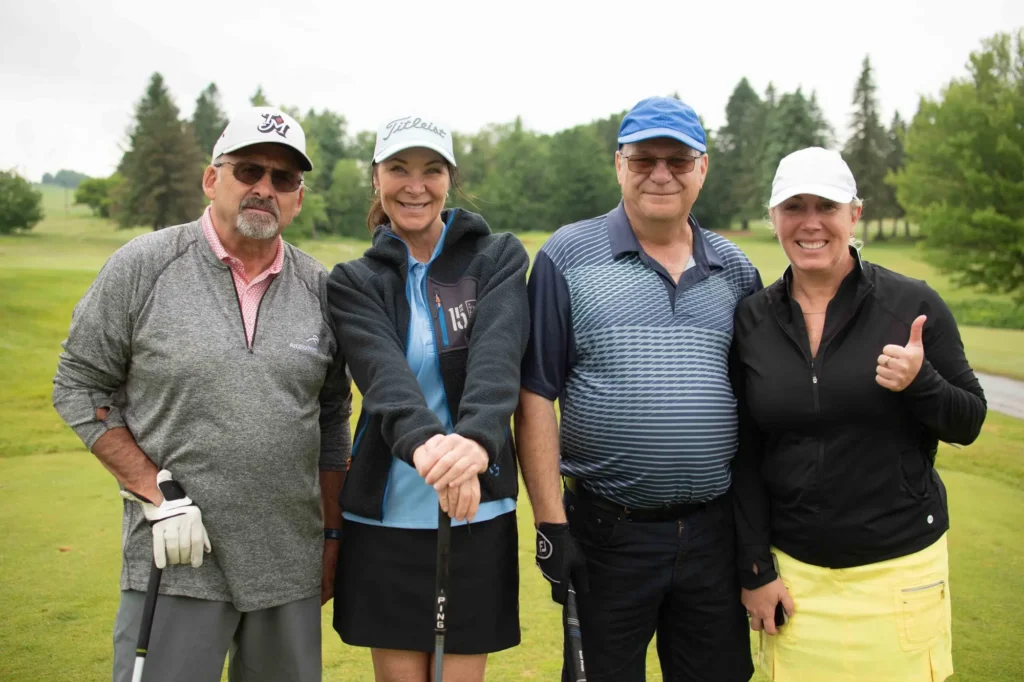 Quatre golfeurs souriants sur un parcours verdoyant