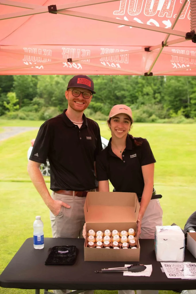 Deux personnes souriantes vendent des cupcakes en plein air