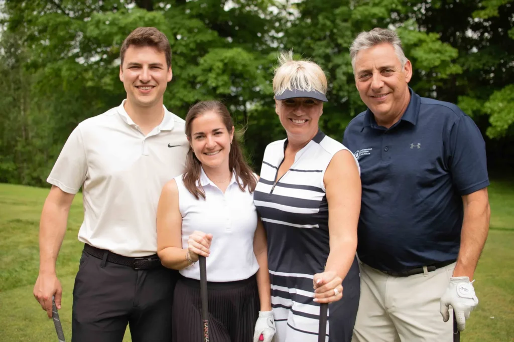 Quatre golfeurs souriants sur un parcours verdoyant