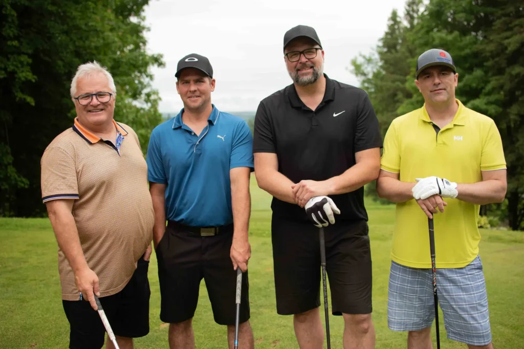 Quatre hommes posant sur un parcours de golf