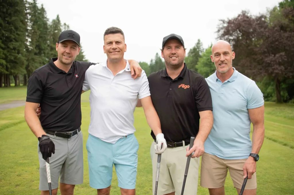 Quatre hommes posant sur un parcours de golf