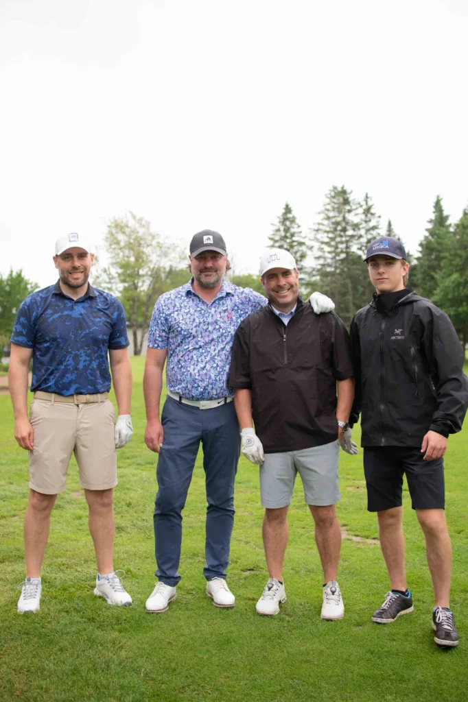 Quatre hommes posant sur un parcours de golf