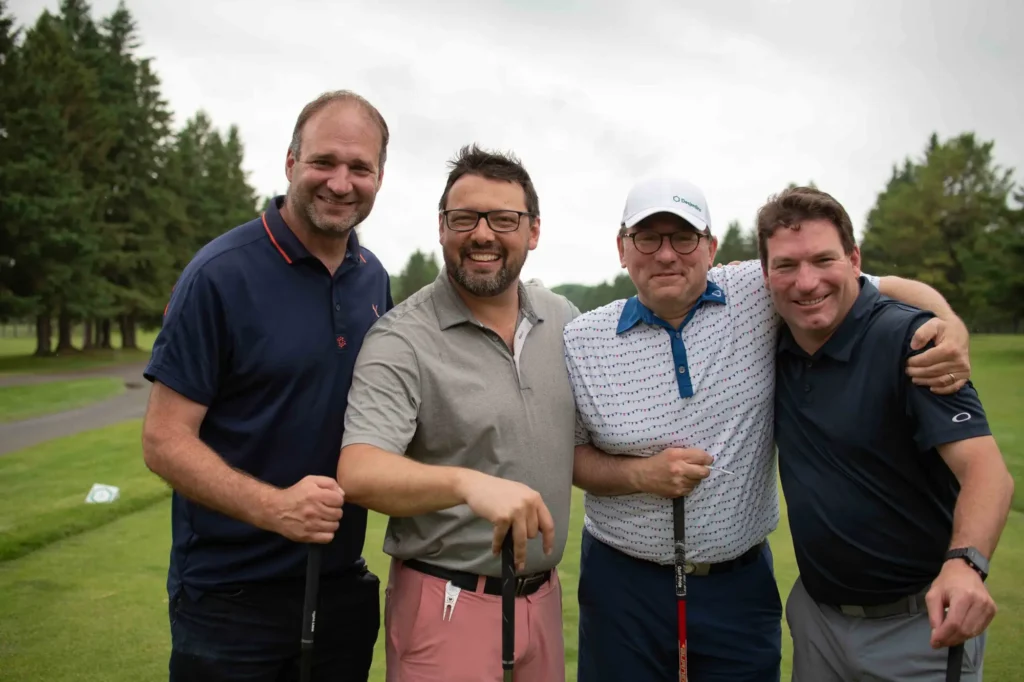 Quatre hommes souriants sur un parcours de golf