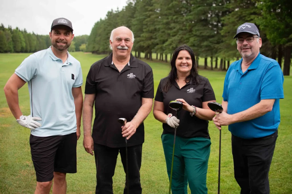 Quatre golfeurs posant sur un parcours verdoyant