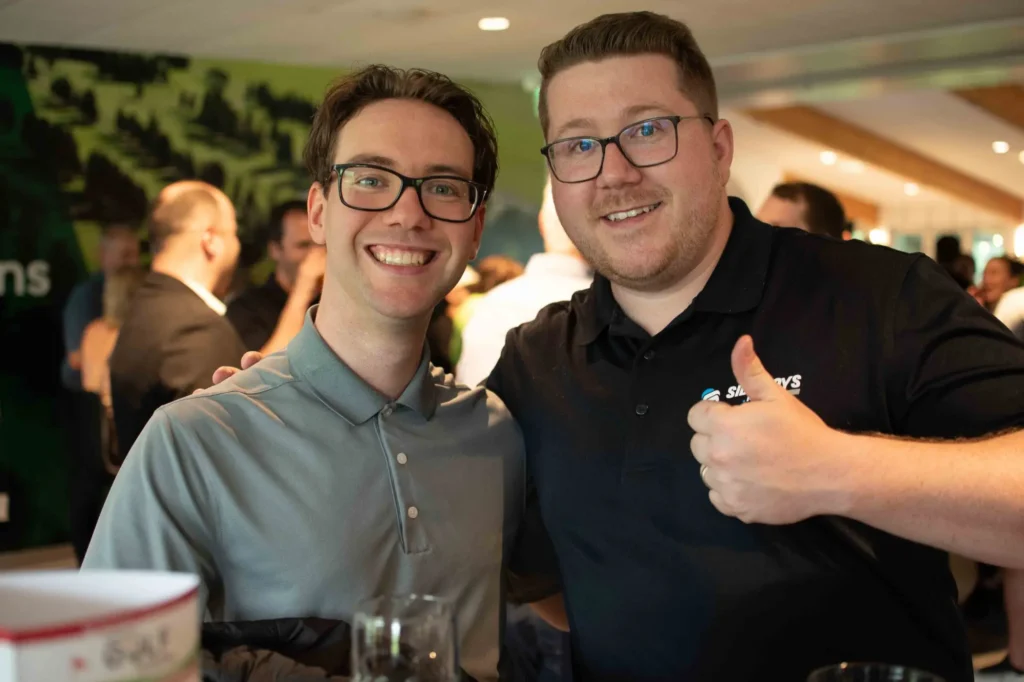 Deux hommes souriants lors d’un événement intérieur