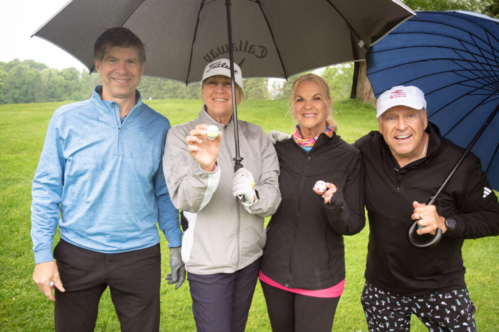 Quatre golfeurs souriants sous la pluie