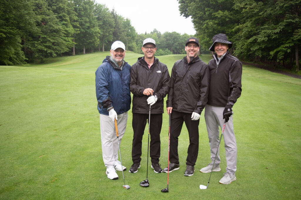 Quatre golfeurs posant sur un parcours verdoyant