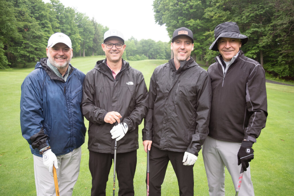 Quatre golfeurs sous la pluie sur un parcours