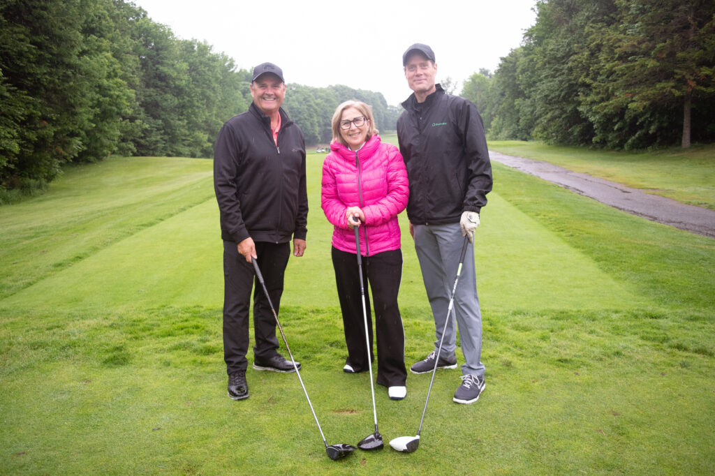 Trois golfeurs souriants sur un parcours verdoyant