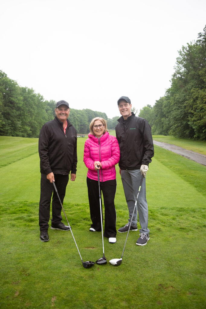 Trois golfeurs souriants sur un parcours verdoyant