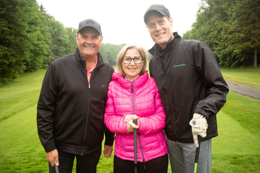 Trois golfeurs souriants sur un parcours verdoyant