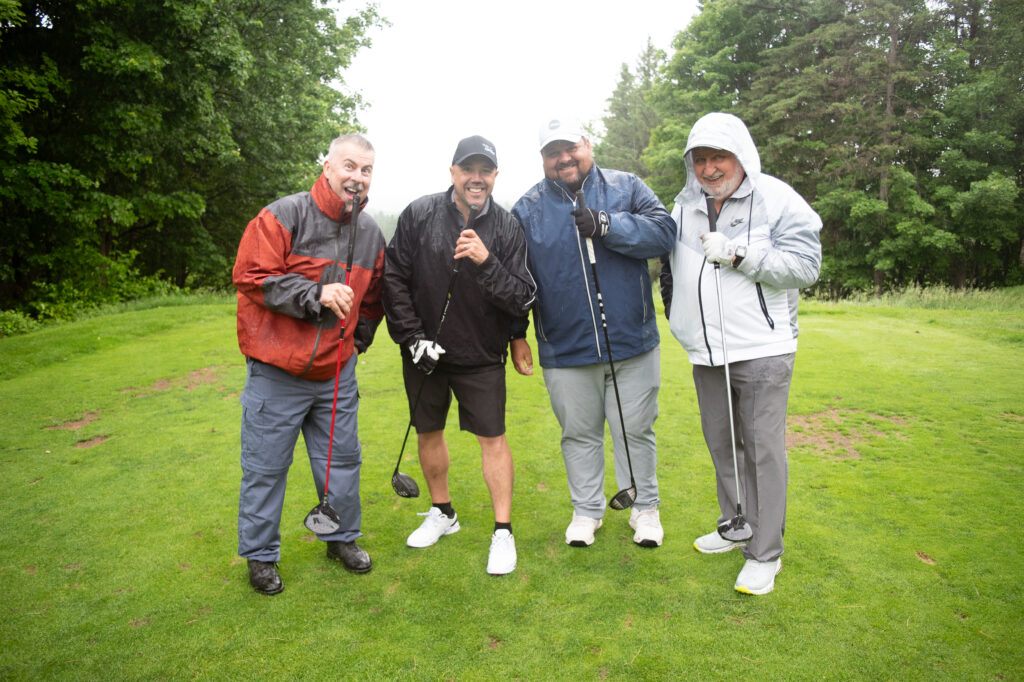 Quatre golfeurs souriants sous la pluie