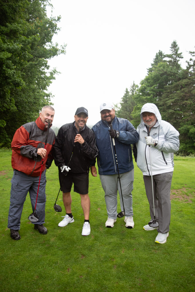 Quatre golfeurs souriants sous la pluie