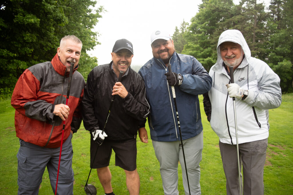 Quatre golfeurs souriants sous la pluie